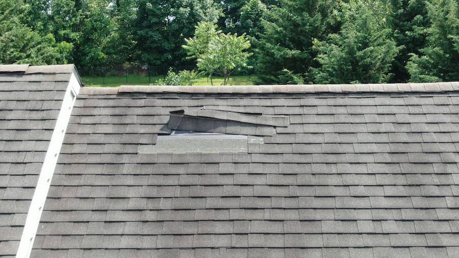 Storm-damaged asphalt shingle roof awaiting professional replacement