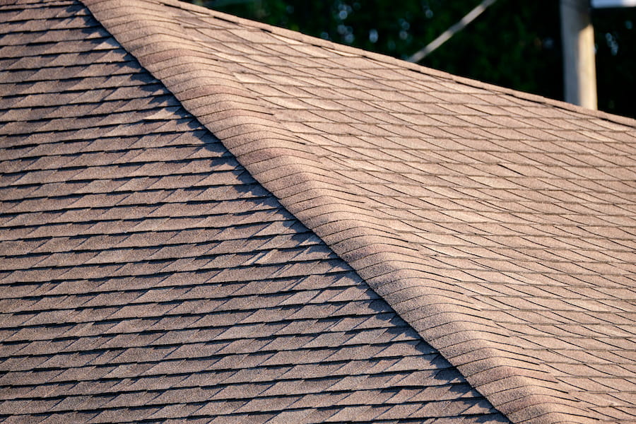 Closeup of house roof top covered with asphalt or bitumen shingles. Waterproofing of new building