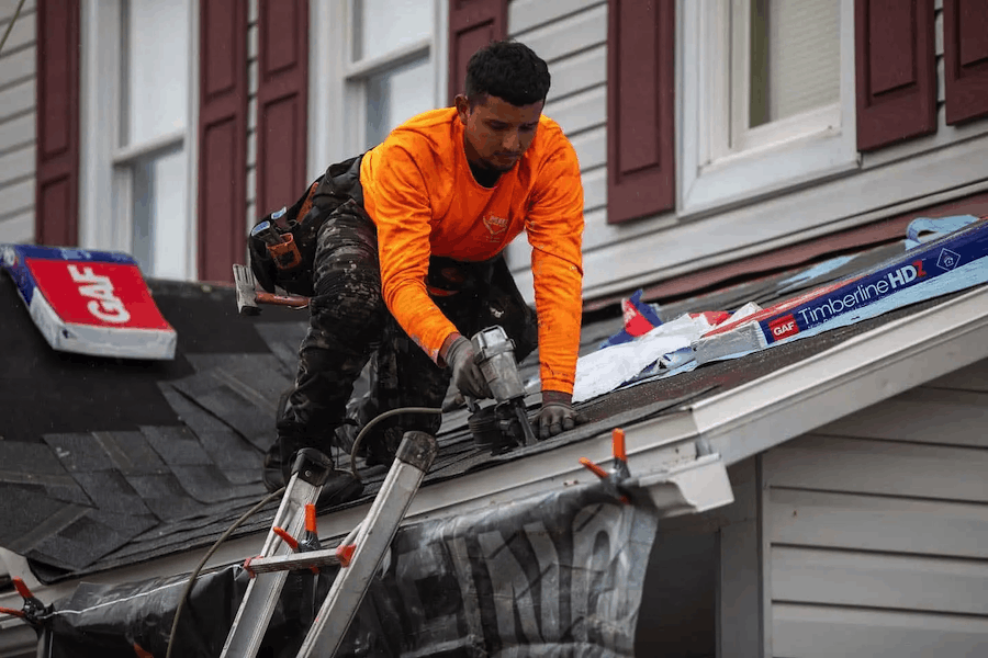 Roofing professional inspecting a residential roof for damage